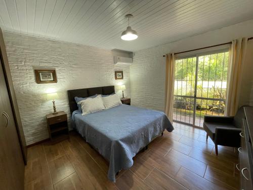 1 dormitorio con 1 cama, 1 silla y 1 ventana en Magnolio, en Colonia del Sacramento