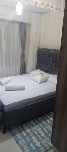 um quarto com uma cama com lençóis brancos e uma janela em Tj homes-Airportview em Nairobi