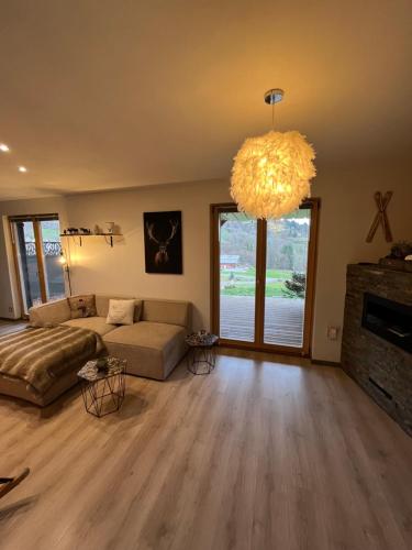 a living room with a couch and a chandelier at Le chalet de cathy in Soultzeren