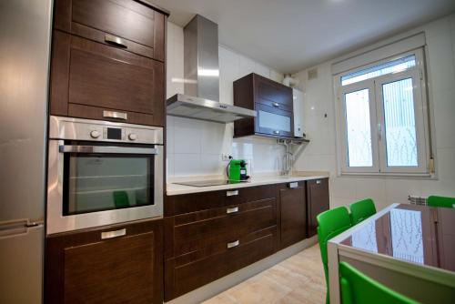 a kitchen with wooden cabinets and a table with green chairs at Céntrico Apartamento in A Coruña