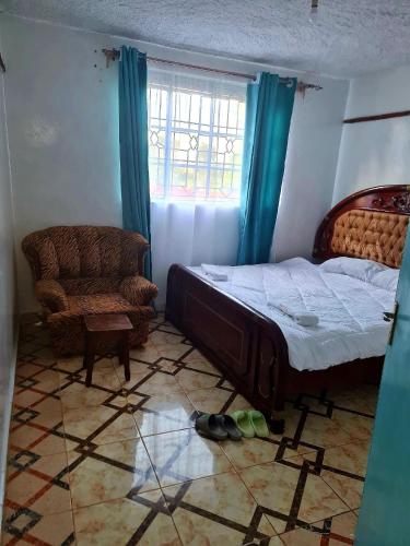 ein Schlafzimmer mit einem Bett, einem Stuhl und einem Fenster in der Unterkunft Dala kwe in Siaya