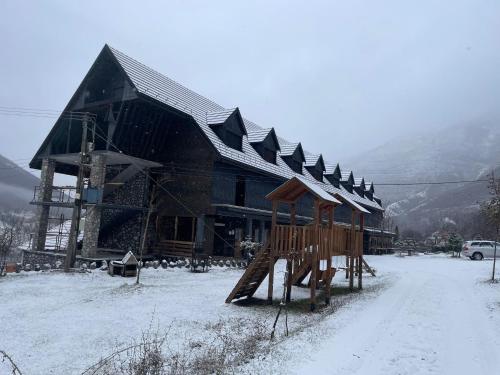 a large wooden building with a snow covered roof at Boga Alpine Resort in Bogë