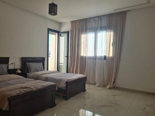 1 dormitorio con 2 camas y ventana grande en Wilaya Center Suites, en Tetuán