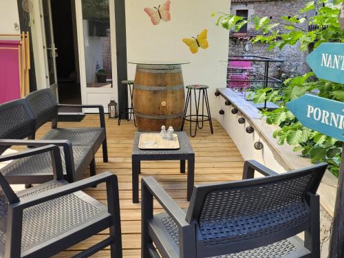 une terrasse avec trois chaises et un tonneau dans l'établissement PETIT PARADIS, à La Bruffière