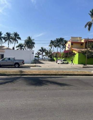 a street with cars parked in a parking lot with palm trees at Dpto. a unos pasos de la playa en Las Brisas in Manzanillo
