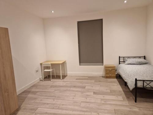 a bedroom with a bed and a table and a desk at Spacious single bedrooms in central location with parking in New Barnet