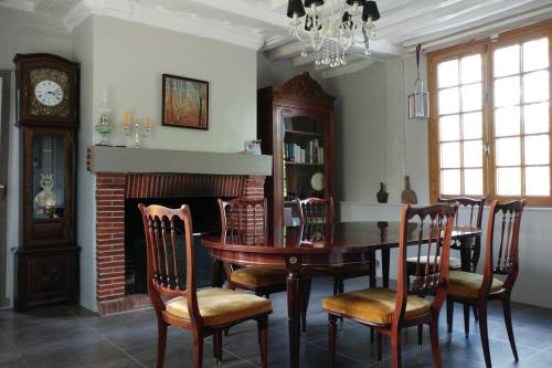 une salle à manger avec une table, des chaises et une cheminée dans l'établissement Maison du 18e avec parc arboré, à 45 min de la mer, à Nassandres