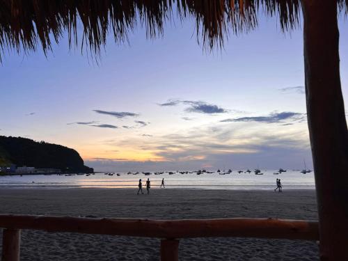 a group of people walking on the beach at sunset at Buena Onda Backpackers in San Juan del Sur