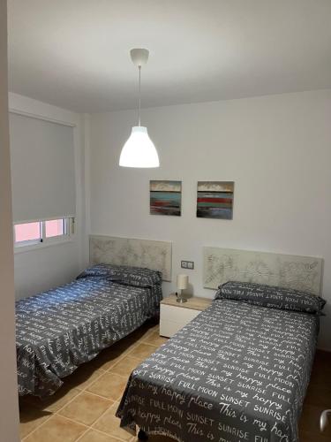 a bedroom with two beds and a pendant light at MOJACAR WITH POOL, BEACH AND GoLF in Mojácar
