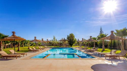 a swimming pool with lounge chairs and umbrellas at Villa Leila Farmhouse in Marrakech