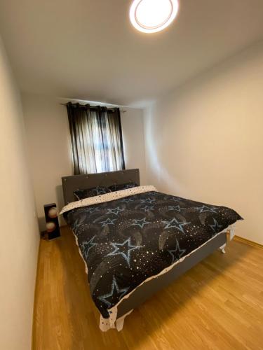 a bedroom with a bed with a black comforter at Apartman Atos stan na dan in Prijedor