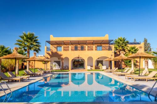 a resort with a swimming pool with chairs and umbrellas at Villa Leila Farmhouse in Marrakech