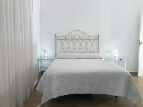 a white bedroom with a bed with a white bedspread at Centrico alojamiento in Jaén