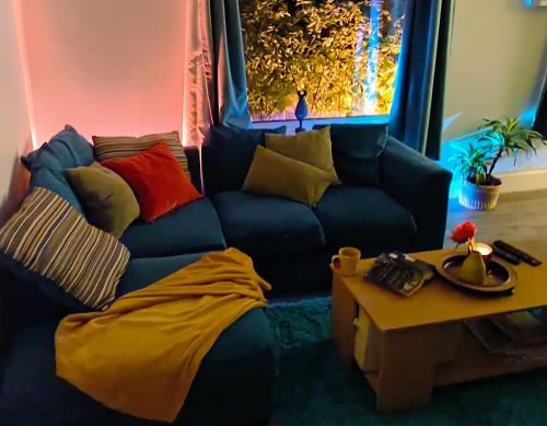 a living room with a blue couch with colorful pillows at Private Entire House - 3 Bedrooms Garden Parking in Rottingdean