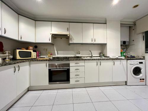 a kitchen with white cabinets and a washer and dryer at Apartamento Compartido con Vista al Puerto Valencia in Valencia