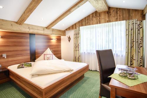 a bedroom with a bed and a desk and a chair at Pension Wendelstein in Miesbach