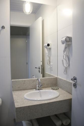 a bathroom with a sink and a mirror at Vincenzo Hotel in São Vicente de Minas