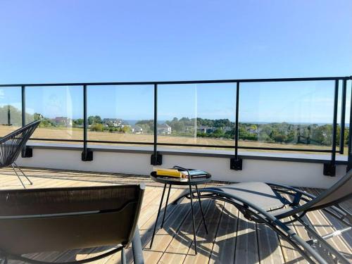 a balcony with a table and chairs in front of windows at Villa Bréhat vue mer et jacuzzi in Tréveneuc