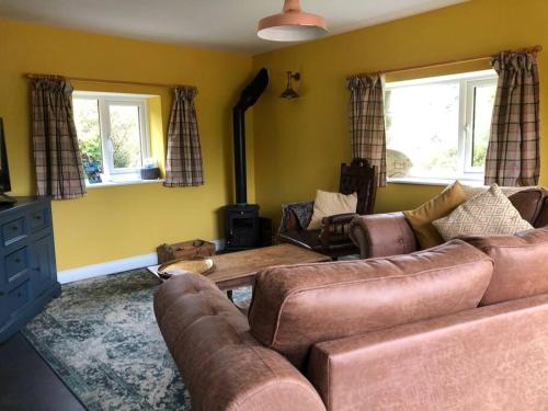 a living room with a couch and two windows at Rhedyn - Cosy Fishing Lodge Near Aberaeron in Cross Inn
