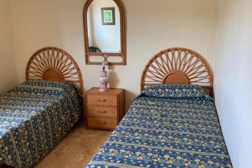 a bedroom with two beds and a mirror at Apartamento de lujo mar y montaña para todo el año con calefacción spa gimnasio y piscina climatizada in Tavernes de Valldigna