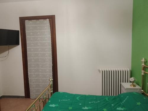 a bedroom with a green bed and a mirror at Casa Artemis (Artemis House) in Cerreggio