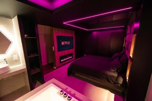 Habitación púrpura con cama y TV en LV Suites Jaude, en Clermont-Ferrand