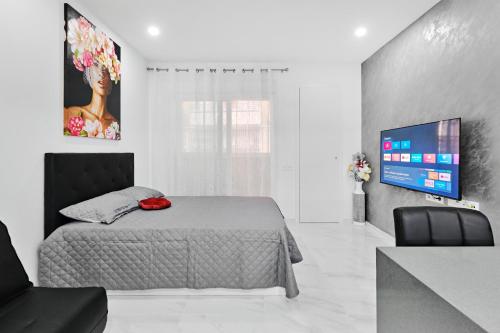 a bedroom with a bed and a flat screen tv at Centro Modern Beach & Spa in Torrevieja