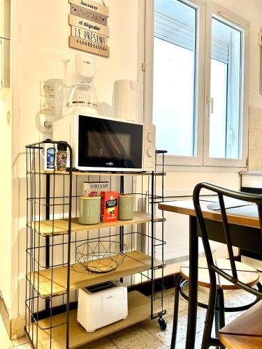 une télévision sur un support dans une pièce avec une table dans l'établissement Le Nairobi, Abbeville, à Abbeville