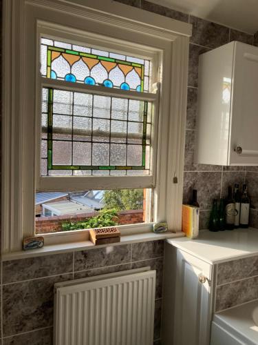 uma cozinha com um vitral e um lavatório em Beautiful sunlit rooms, 2 mins from beach, private garden em Bridlington