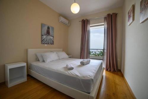 a bedroom with a large bed with a window at Avatonblue Villa Nafplio in Vivari