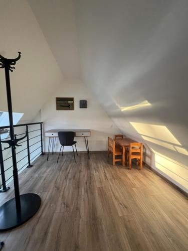 Cette chambre mansardée comprend un bureau et une table. dans l'établissement Maison rénovée au calme, à Biéville-Beuville