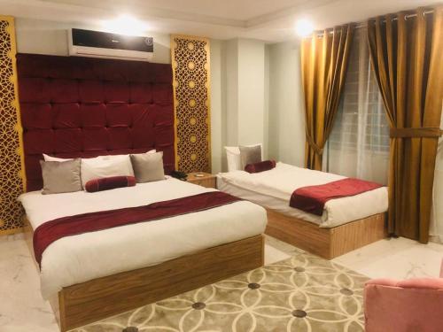 a bedroom with two beds and a red headboard at NuvaHotel in Islamabad