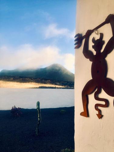 uma escultura de um lagarto numa parede ao lado de um corpo de água em Casita Volcan Lanzarote em Ye
