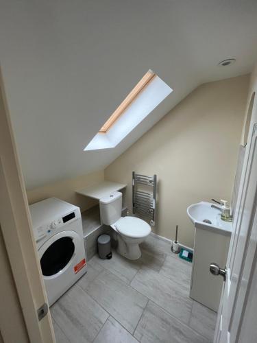 a bathroom with a toilet and a washing machine at L-Houses in Dagenham