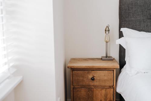 a nightstand with a lamp on it next to a bed at Manor Court in Penzance