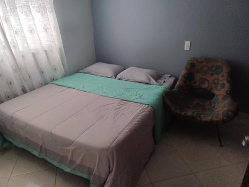 a small bedroom with a bed and a chair at Hermoso y cómodo Apartamento in Envigado