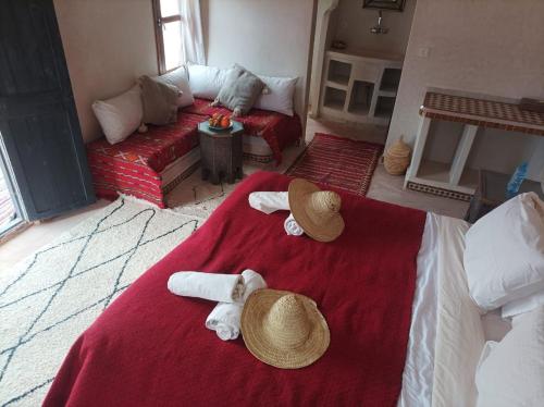 - une chambre avec des serviettes et des chapeaux sur un lit dans l'établissement Zaila Erg Chigaga Luxury Camp, à M'Hamid El Ghizlane