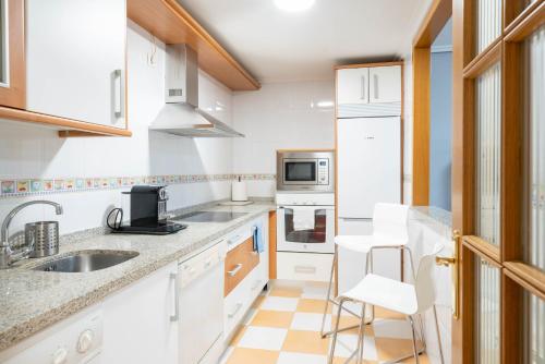 uma cozinha com armários brancos e electrodomésticos brancos em Apartamento Go - La Ermita em Arroyo de la Encomienda