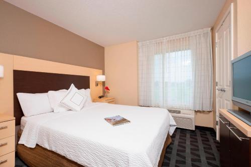 a hotel room with a bed and a television at TownePlace Suites Des Moines Urbandale in Johnston