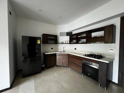 a kitchen with wooden cabinets and a black refrigerator at Sabaneta-Apto familiar in Sabaneta