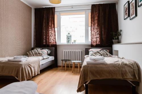 Duas camas num pequeno quarto com uma janela em M&M Apartment em Człuchów