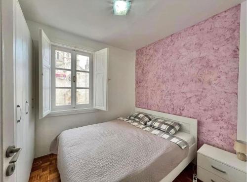 - une chambre avec un mur d'accent rose et un lit dans l'établissement Apartment Old town Milica, à Herceg-Novi