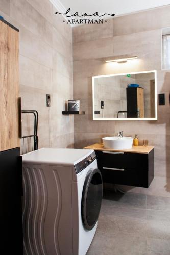 a bathroom with a washing machine and a sink at Lana apartman in Makó