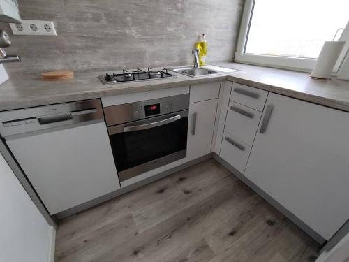 cocina con armarios blancos, fogones y fregadero en Studio Apartment in City Center, en Sindelfingen