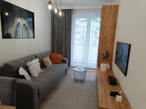 a living room with a gray couch and a large window at Amaprament Do Poznania self check-in 24h, free parking in Poznań