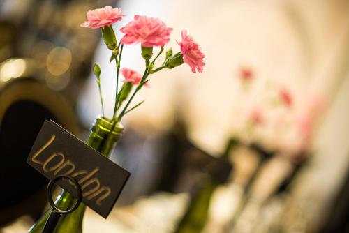 a vase filled with pink flowers with a pair of scissors at Mama’s Inn Boutique Guest House in Nottingham