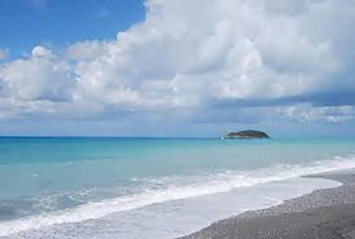 a beach with a small island in the ocean at Red Stone in Diamante
