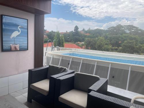 a balcony with chairs and a view of a swimming pool at Kantree House - Safari Suites in Kampala