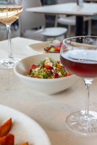 a bowl of salad and a glass of wine on a table at Casa 1810 Parque Hotel Boutique in San Miguel de Allende