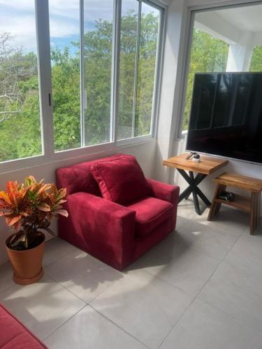 einen roten Stuhl im Wohnzimmer mit einem TV in der Unterkunft Amarilla (Amar y ya) in Cuatunalco